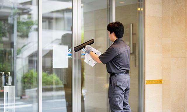 足立区の賃貸マンション共用玄関を磨く清掃スタッフ